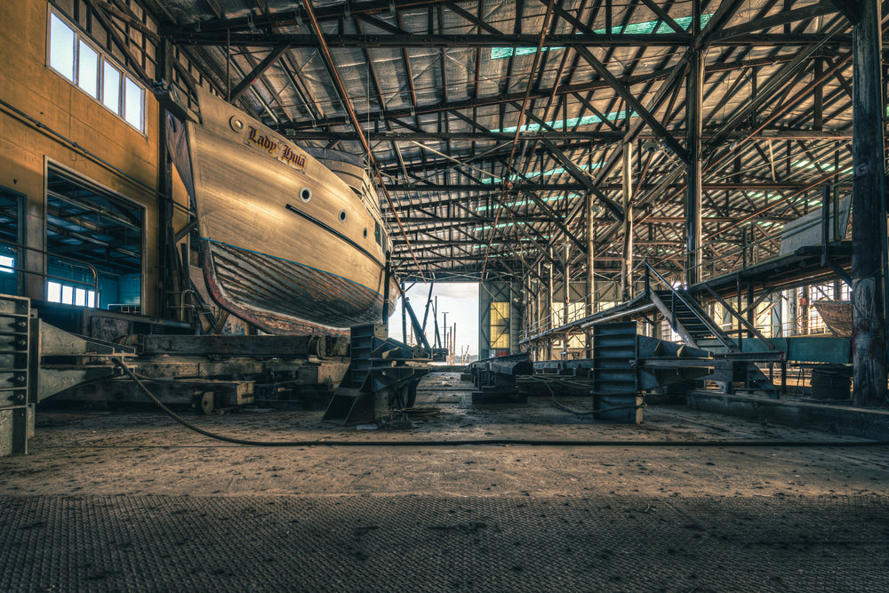 Beneath the Boat at Halvorsens Boat Yard, a timber-hulled vessel sits on steel cradle blocks inside the main shed.
