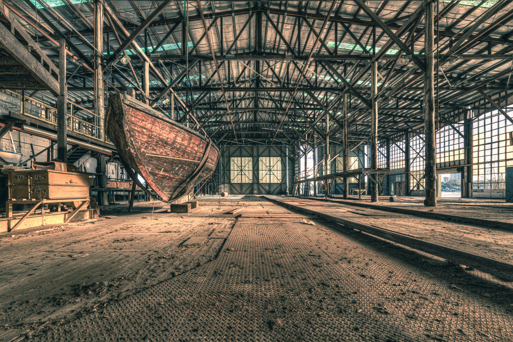 Checkerplate at Halvorsens Boat Yard, a timber hull sits propped on blocks inside a vast industrial shed.