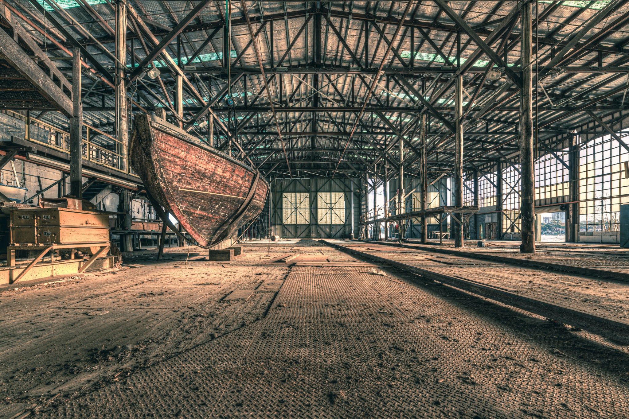 Checkerplate at Halvorsens Boat Yard, a timber hull sits propped on blocks inside a vast industrial shed.