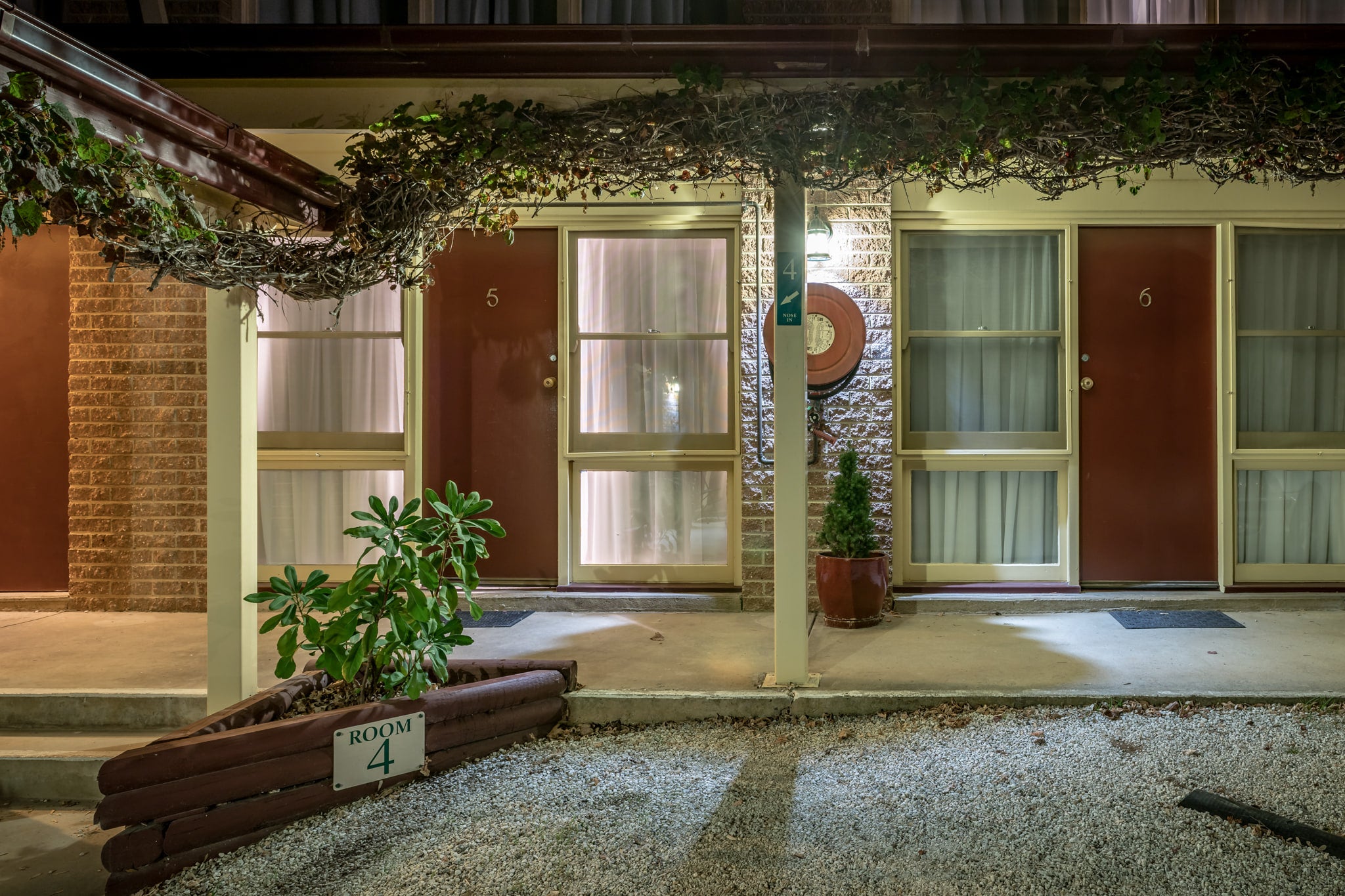 Berrima Bakehouse Motel at Hotel Motel 101, rooms 4, 5 and 6 face a gravel car park under flat fluorescent light.