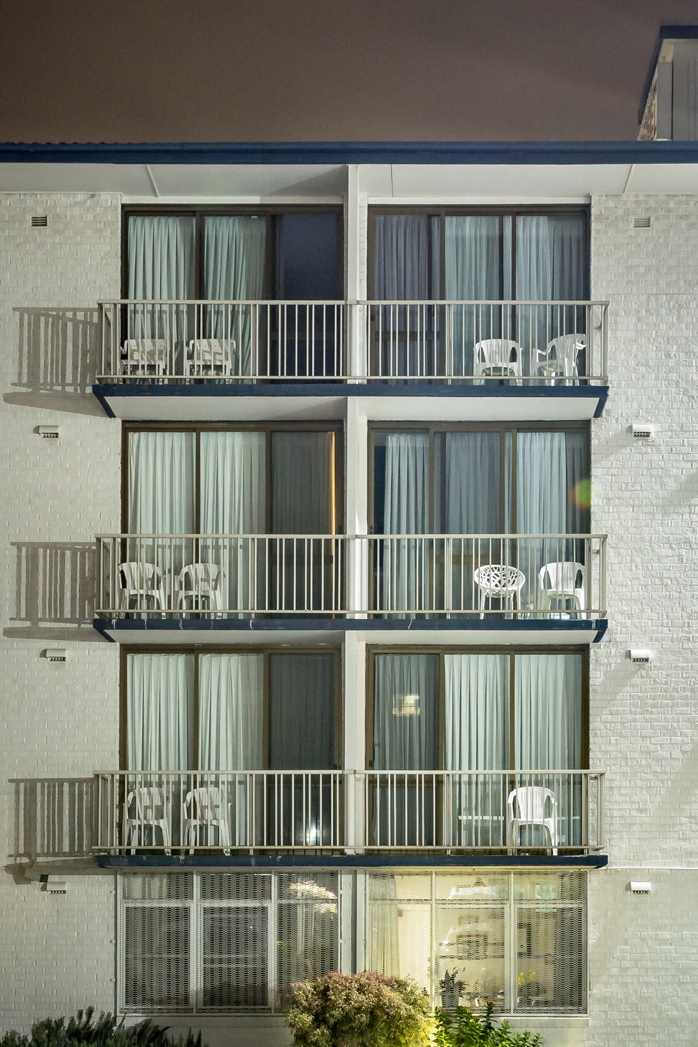 Boat Harbour Motel at Hotel Motel 101, three storeys of white-painted brick rise flat against the night sky.