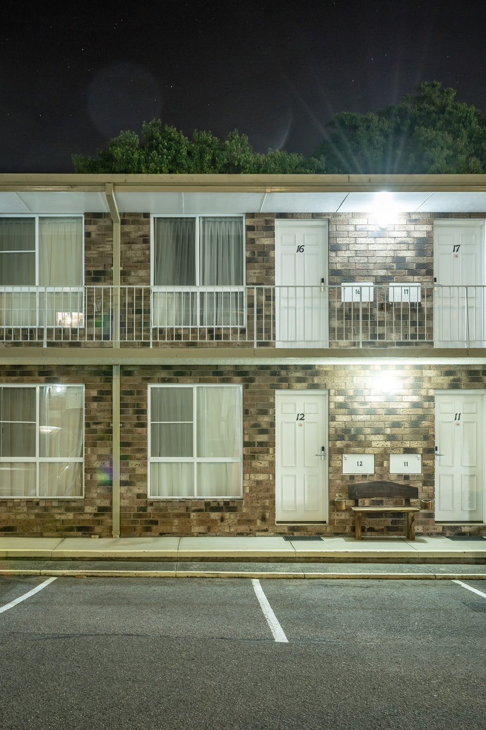 Gosford Palms Motor Inn at Hotel Motel 101, two storeys of brown brick and white panel doors face an empty car park.