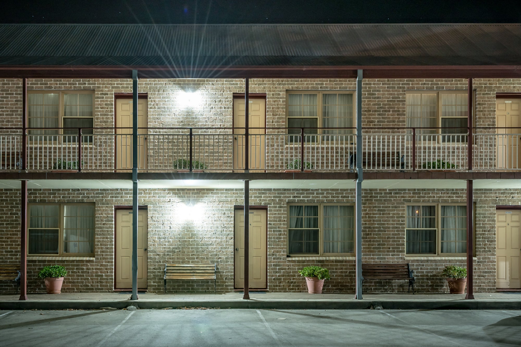 New Inn Motel at Hotel Motel 101, two storeys of brown brick face an empty car park.