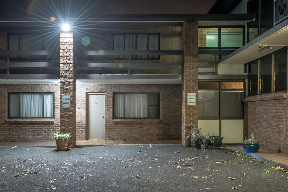 Oasis Resort at Hotel Motel 101, a single security light flares against the brick pillar between storeys, throwing hard.