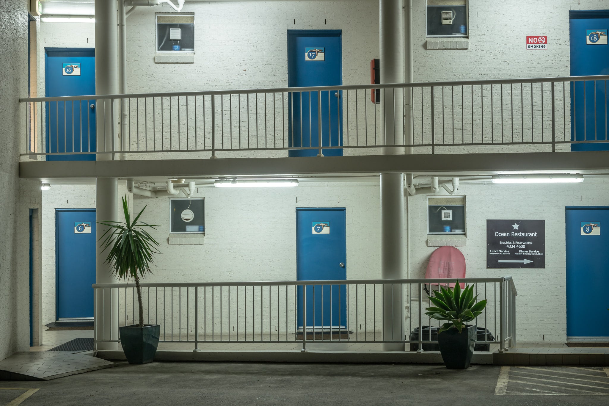 Ocean Front Motel At Blue Bay at Hotel Motel 101, two storeys of painted blockwork and blue steel doors.