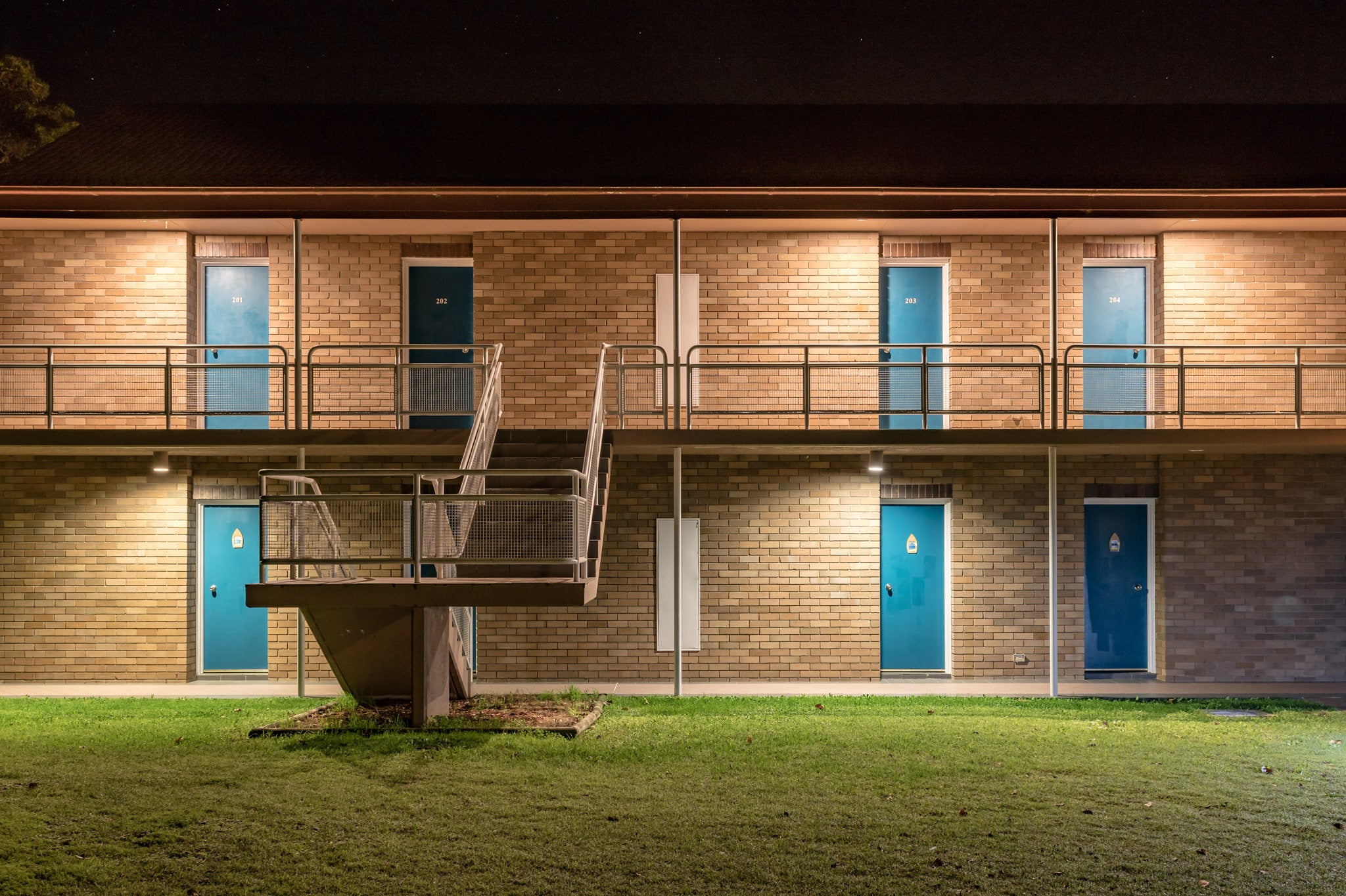 Pacific Garden Hotel at Hotel Motel 101, two storeys of brown brick face the night.