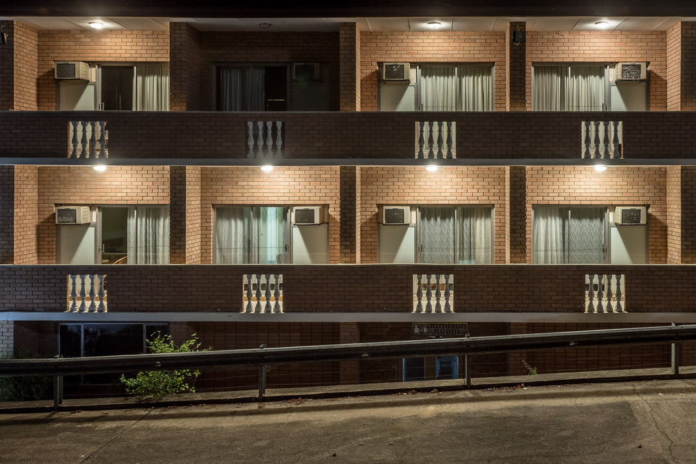 Resteasy Motel at Hotel Motel 101, two storeys of brown brick facade, dead straight, shot front-on at night.
