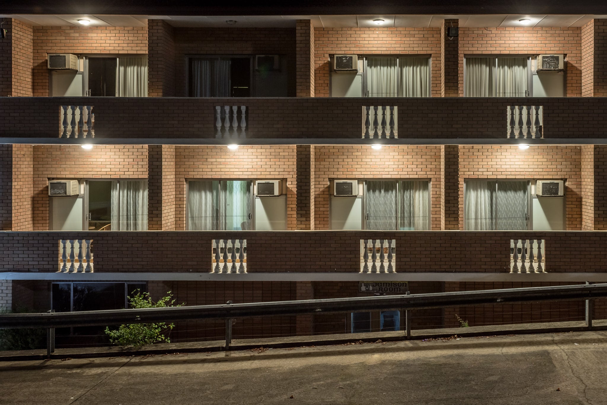 Resteasy Motel at Hotel Motel 101, two storeys of brown brick facade, dead straight, shot front-on at night.