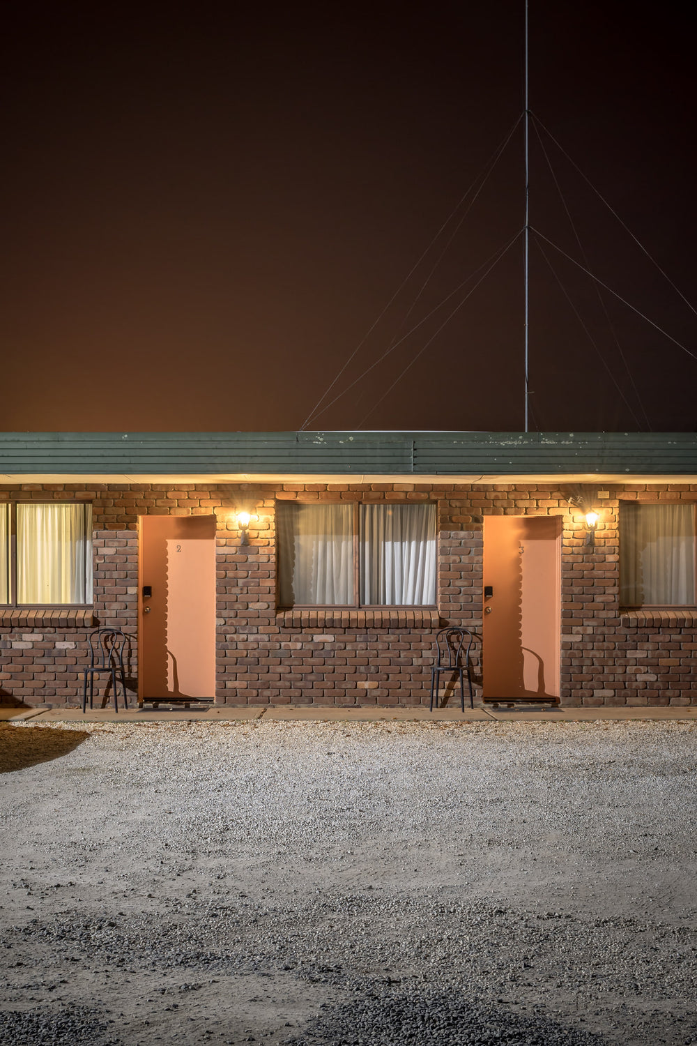 Robertson Country Motel, Robertson at Hotel Motel 101, a gravel car park in front of two motel rooms with a tall aerial.