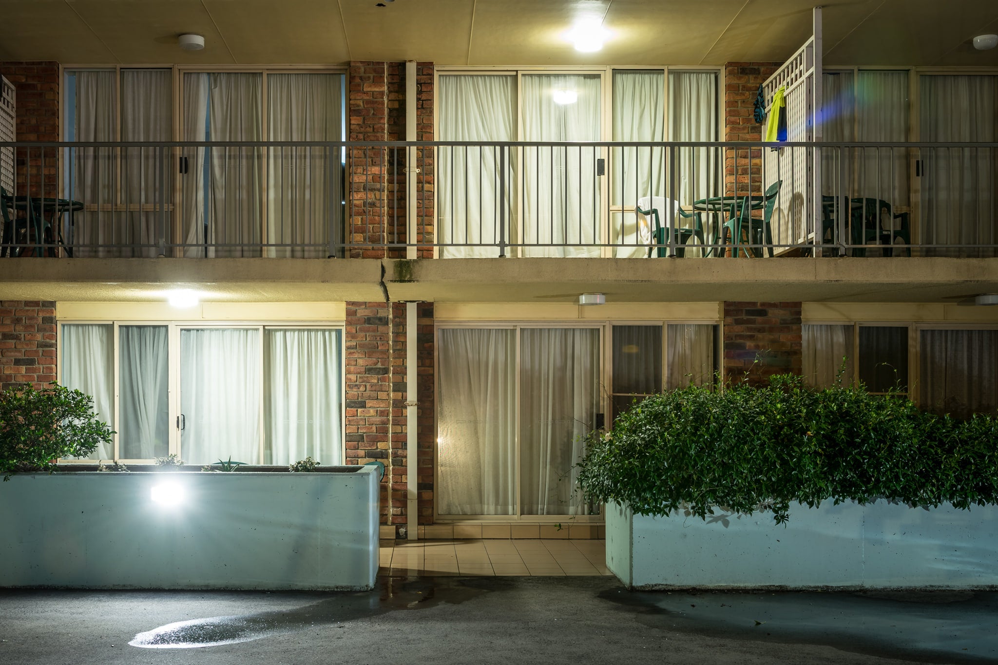 The Beachcomber Motel at Hotel Motel 101, two storeys of brown brick and concrete planter boxes face the carpark.