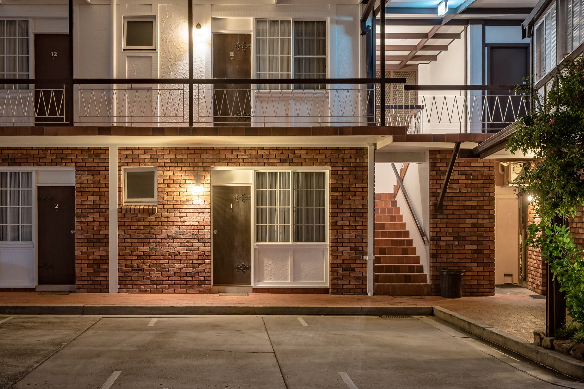 The Clan at Hotel Motel 101, two storeys of brown brick and white render face an empty car park.