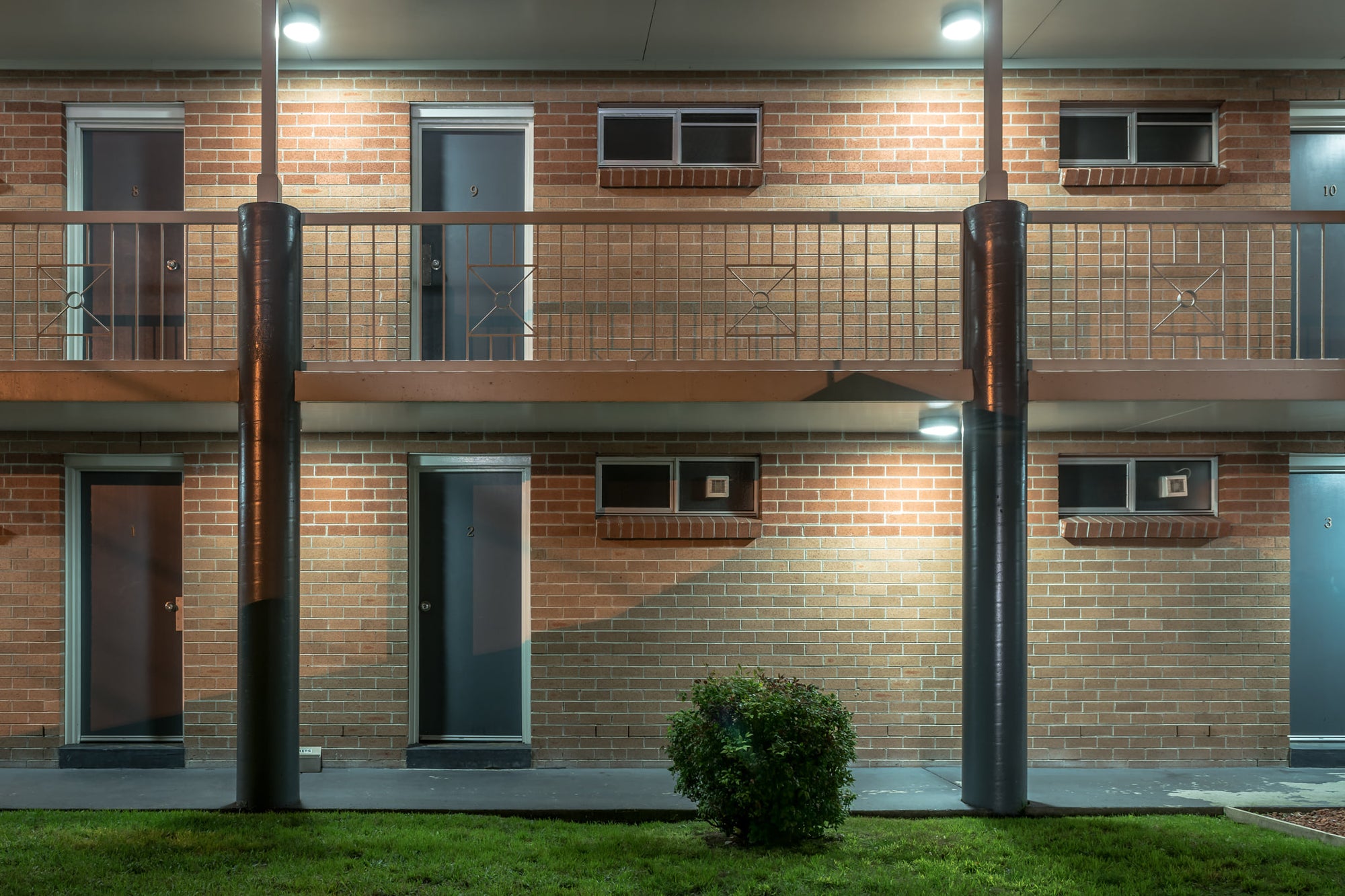 The Oaks Motel at Hotel Motel 101, two storeys of brown brick face the car park under fluorescent security lights.