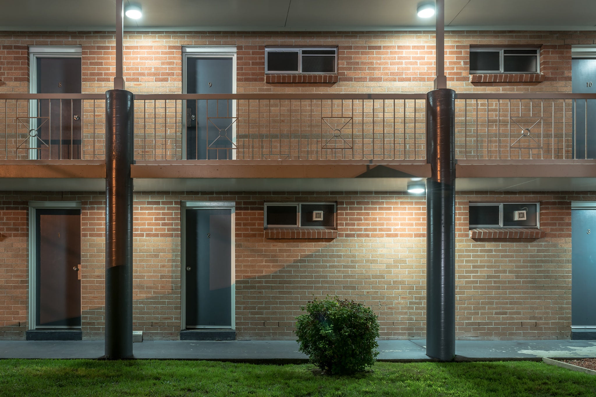 The Oaks Motel at Hotel Motel 101, two storeys of brown brick face the car park under fluorescent security lights.