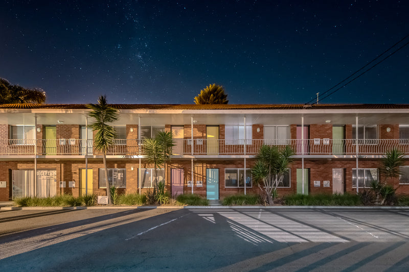 Thirroul Beach Motel, Thirroul at Hotel Motel 101, a red brick motel with pastel coloured doors under a starlit sky.