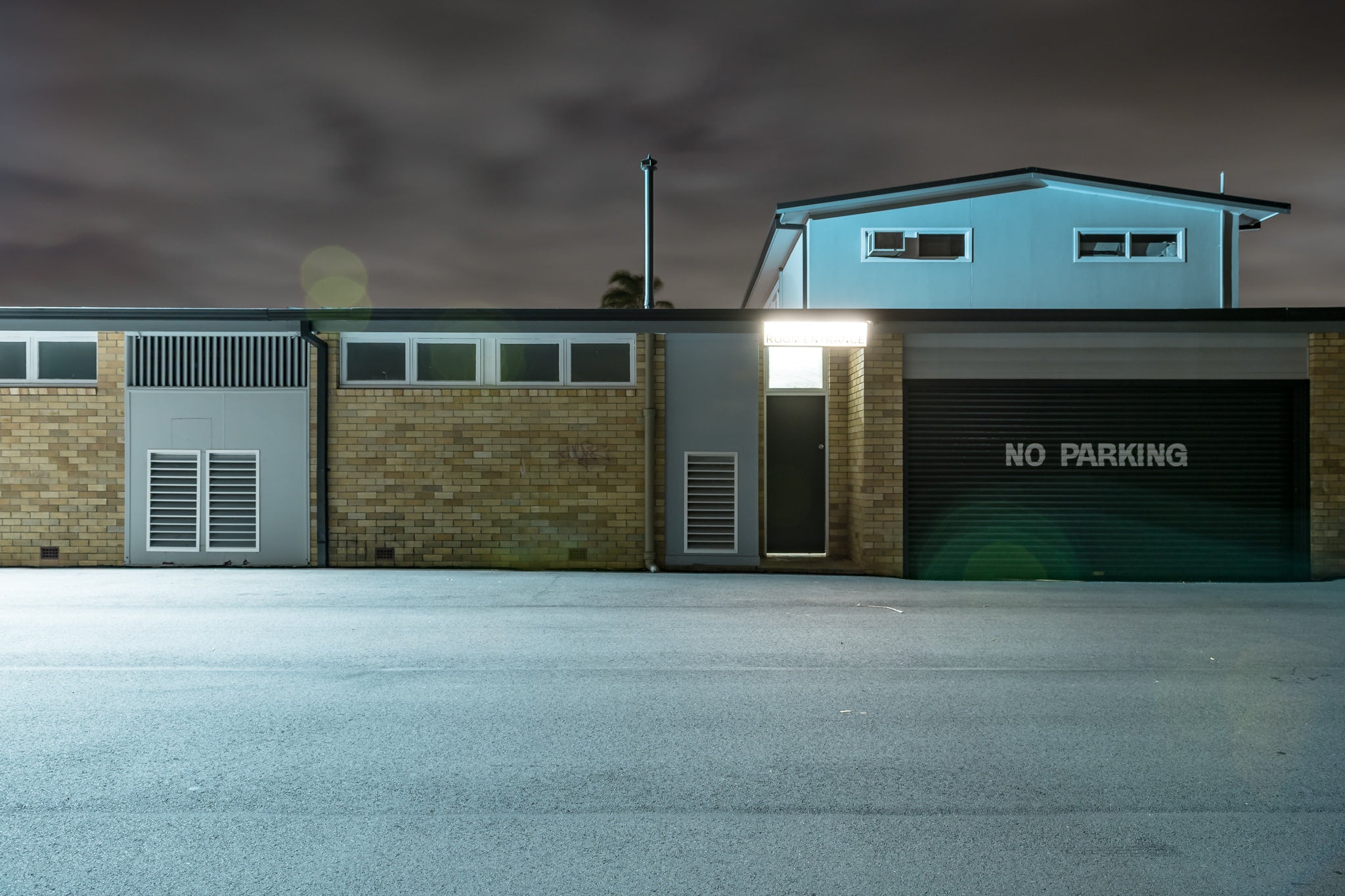 Twin Willows at Hotel Motel 101, a single floodlight burns above a narrow doorway, throwing cold white light.