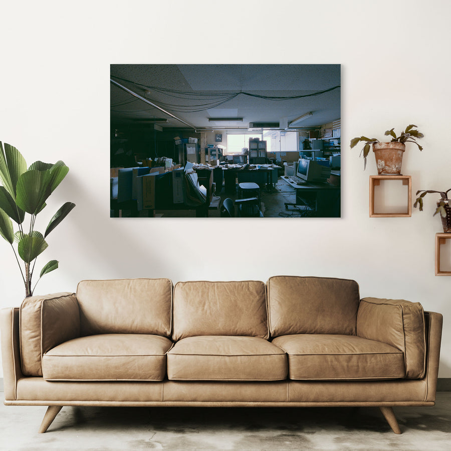 A cluttered desk covered in ring binders, paperwork and a white NEDO box, with a framed flamingo print on the wall above a cabinet, photographed inside the coal mine offices at Ikeshima.