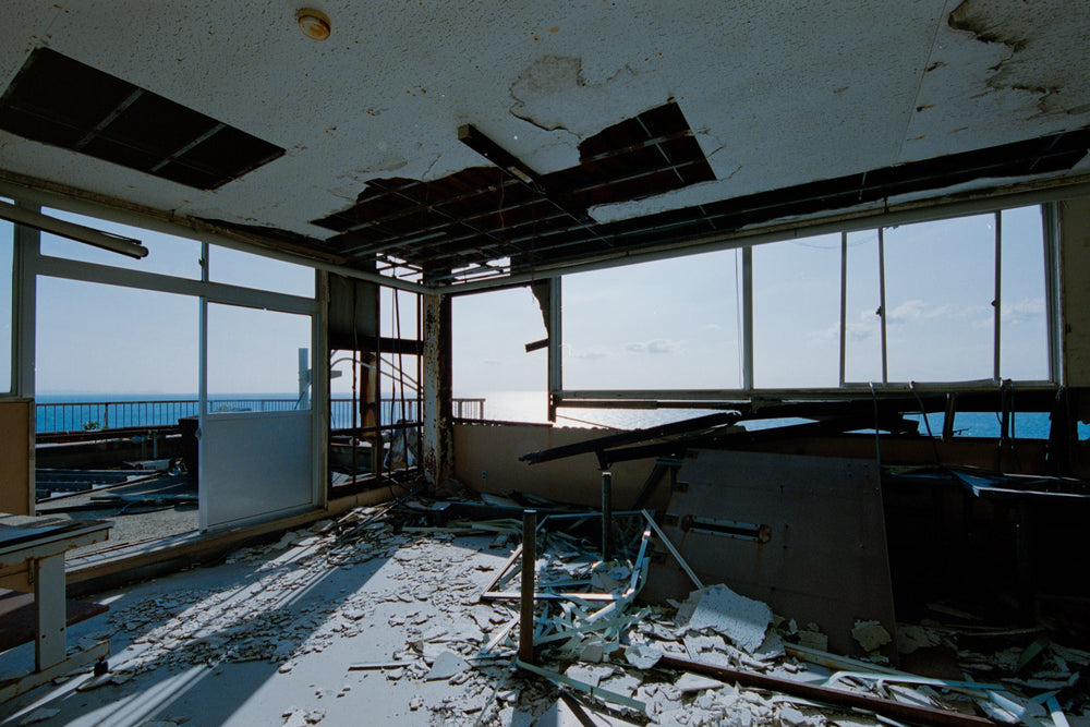 Corner office in the No. 2 Shaft office at Ikeshima Coal Mine, collapsed ceiling and debris with the sea in every window.
