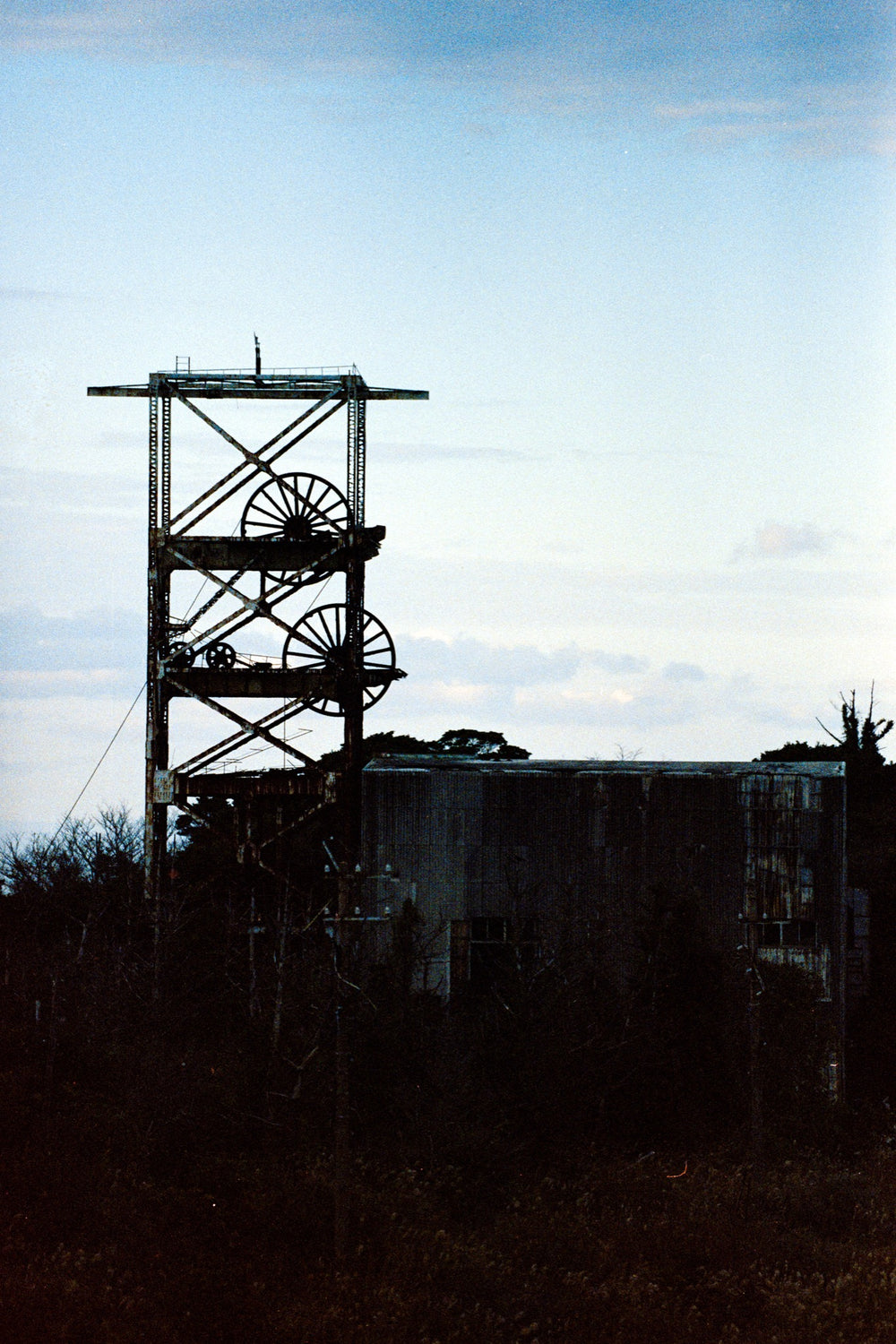 No. 1 shaft headframe at Ikeshima Coal Mine in silhouette at dusk, two head sheaves in the lattice tower.
