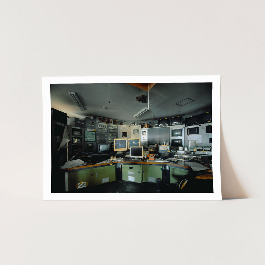 Curved operator console with three beige CRT monitors, orange rotary telephones and instrument panels at the Ikeshima Coal Mine control room.