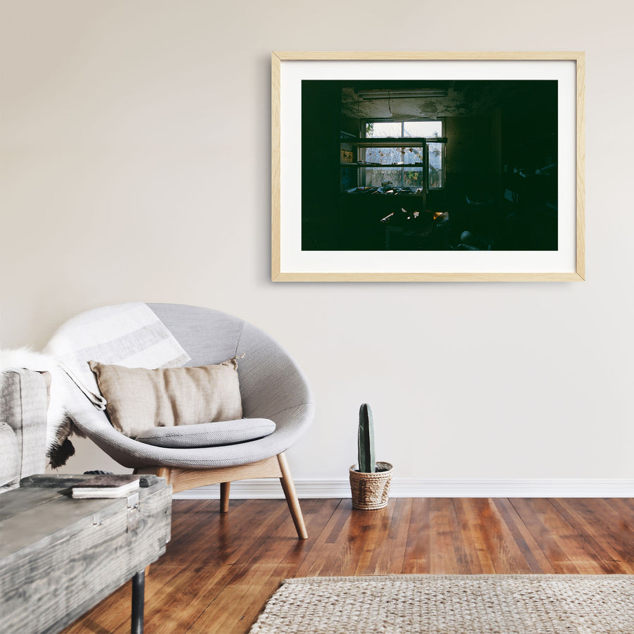 A metal shelving unit stands before a multi-pane window at Ikeshima Coal Mine, vines pressing against the grimy glass outside, with papers and ceramic objects scattered across the shelves and floor.
