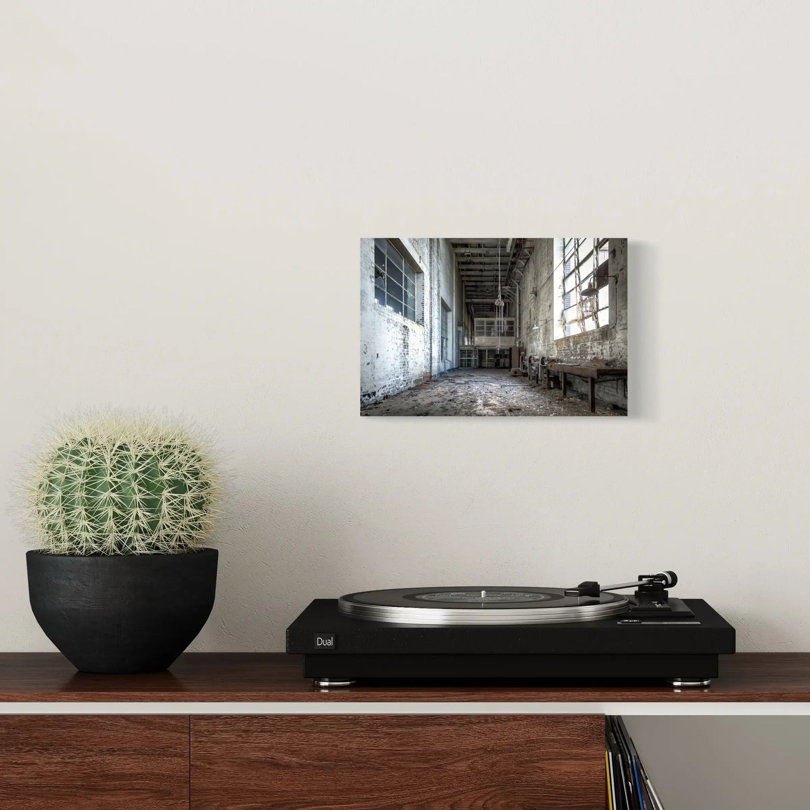Industrial art print on a wall above a wooden shelf and turntable in a modern minimalist room.