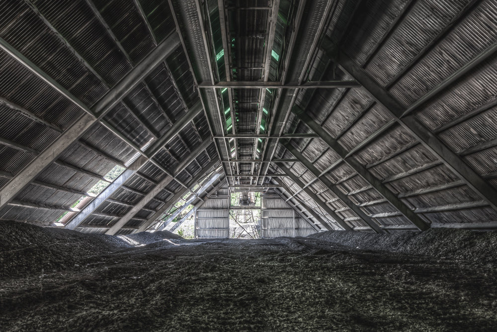 Raw Stone Shed at Kandos Cement Works, dark heaps of crusite and stone dust cover the floor, rising in uneven mounds.