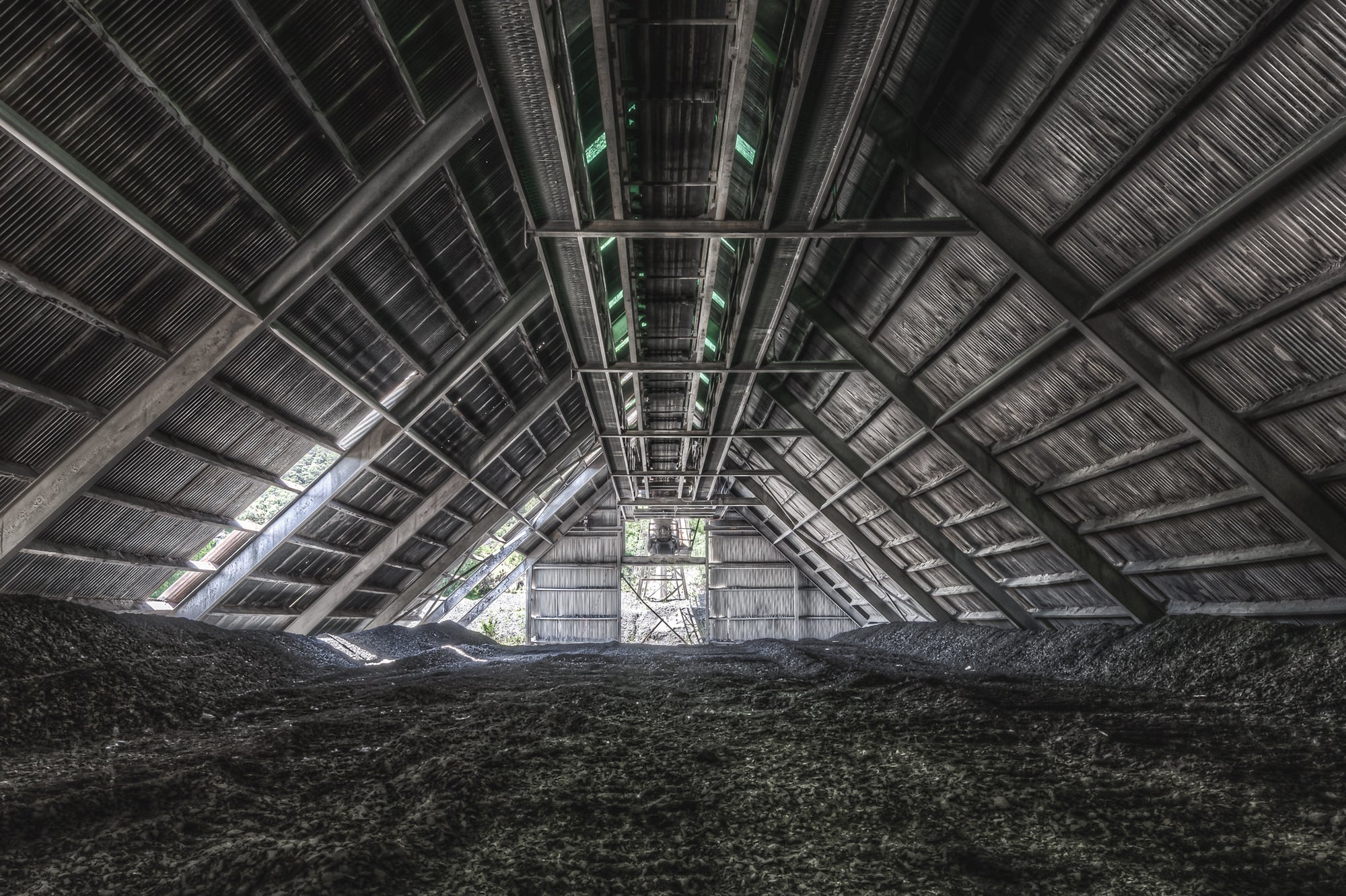 Raw Stone Shed at Kandos Cement Works, dark heaps of crusite and stone dust cover the floor, rising in uneven mounds.