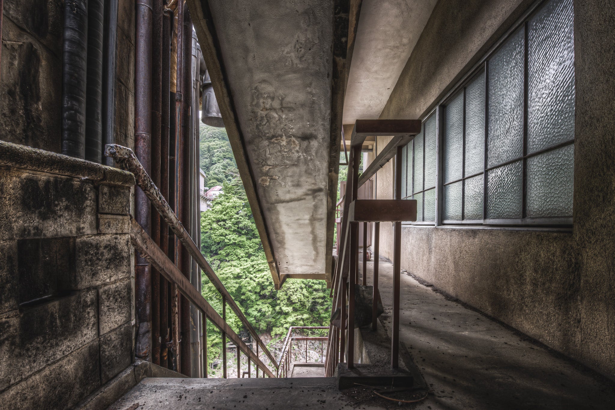 Exterior Fire Exit at Kinugawa Kan, a concrete overhang presses low above an exterior corridor on the upper floors.