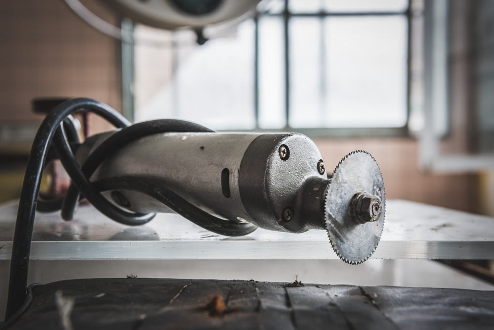 Bone Saw at Kuwashima Hospital, a cast-cutting saw rests on a metal surface, its small circular blade still fitted.