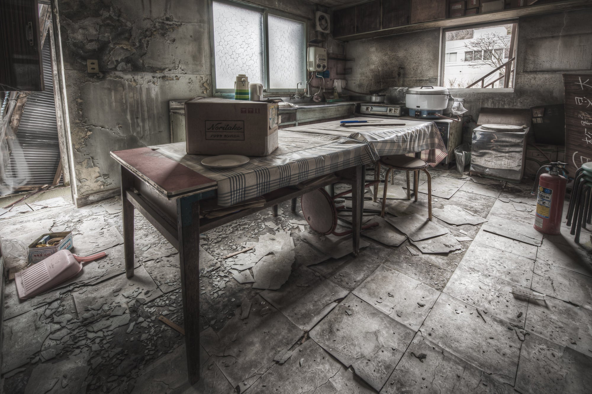 Kitchen And Dining Room at Kuwashima Hospital, a kitchen table sits centre-room, covered in a checked cloth gone grey.