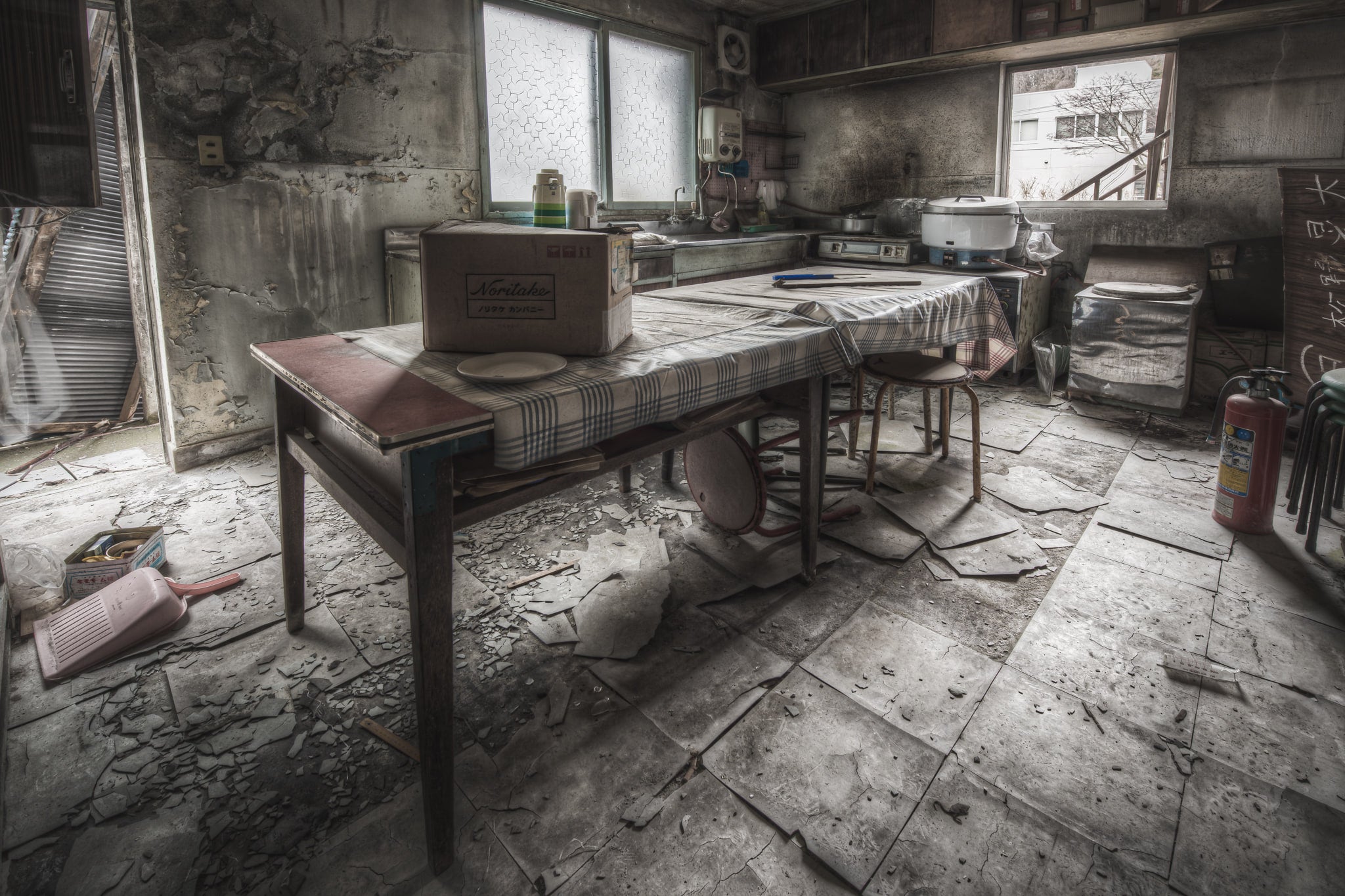 Kitchen And Dining Room at Kuwashima Hospital, a kitchen table sits centre-room, covered in a checked cloth gone grey.