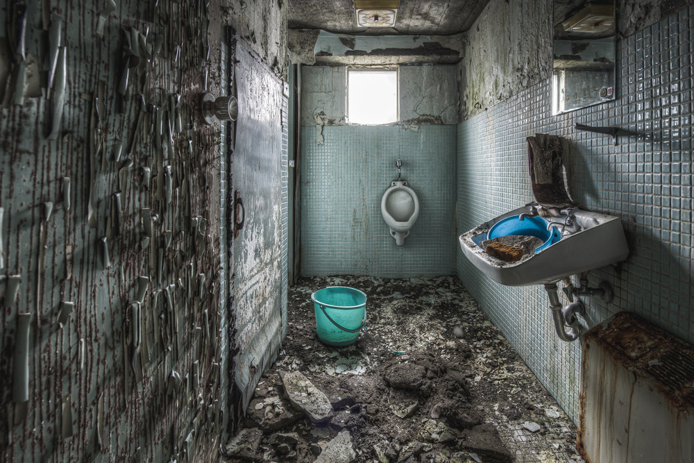 Toilet at Kuwashima Hospital, small blue-green mosaic tiles line the walls of a narrow washroom.