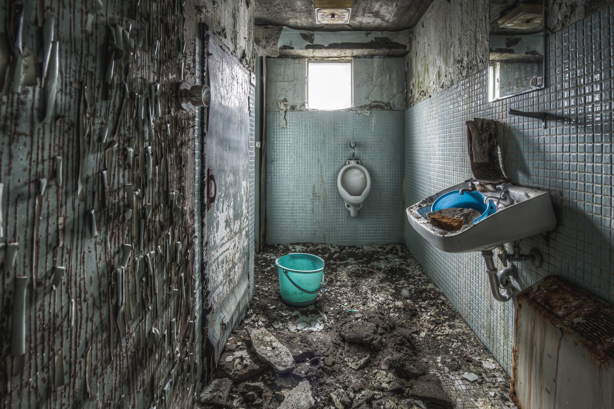 Toilet at Kuwashima Hospital, small blue-green mosaic tiles line the walls of a narrow washroom.