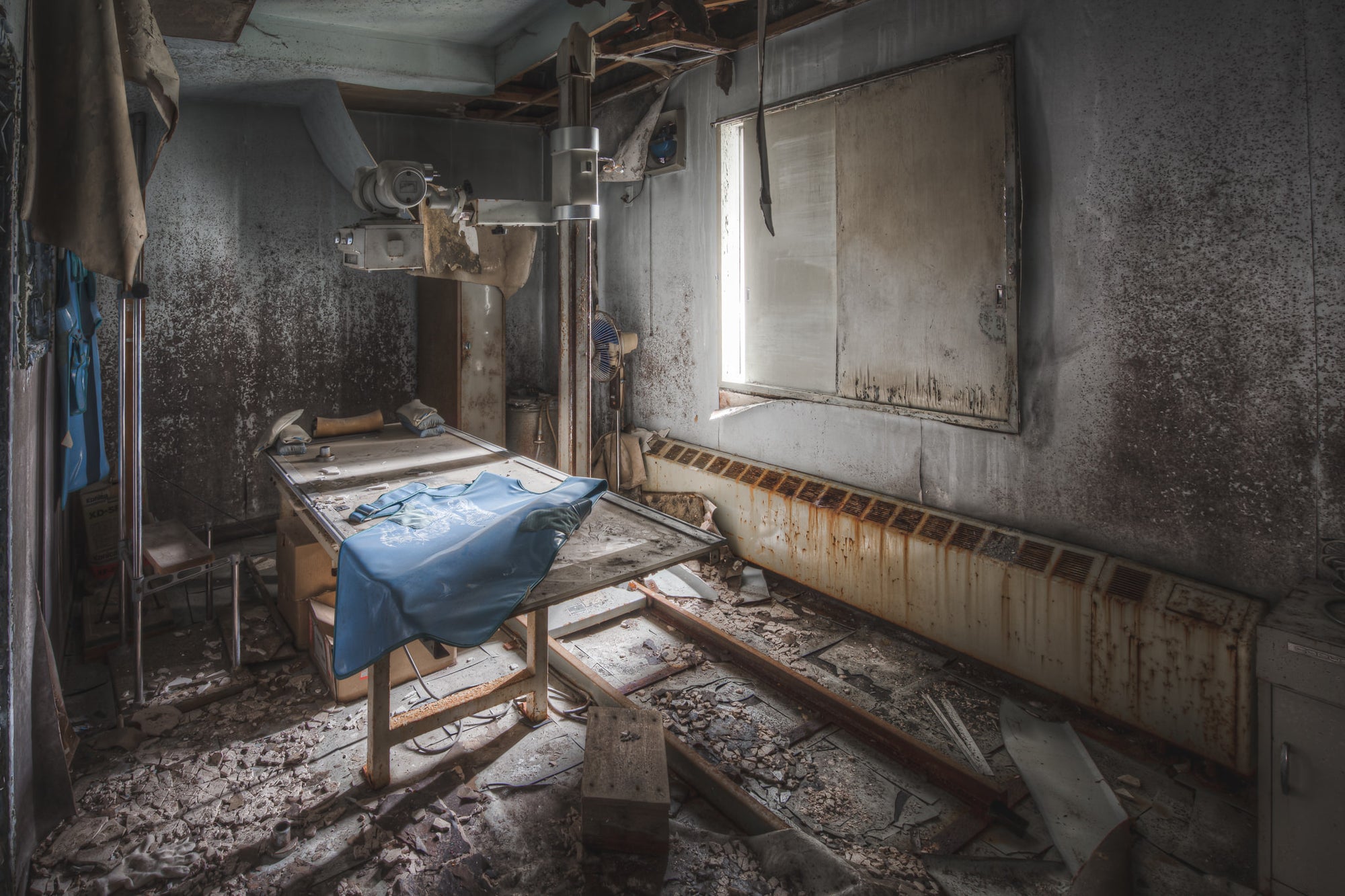 Xray Machine at Kuwashima Hospital, a blue lead apron lies across the X-ray examination table, still draped as though.