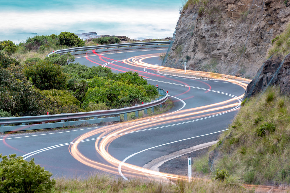 Meander at Landscapes, the Great Ocean Road winds through a cutting in the coastal rock face, the asphalt banking hard through an S-bend.