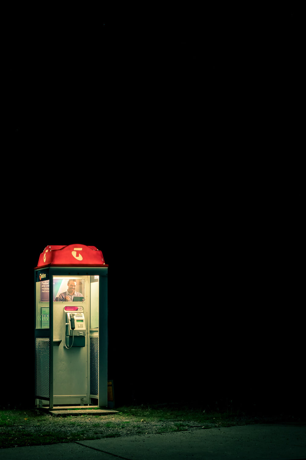 Night Call at Landscapes, a Telstra payphone stands alone at the edge of a roadside verge.