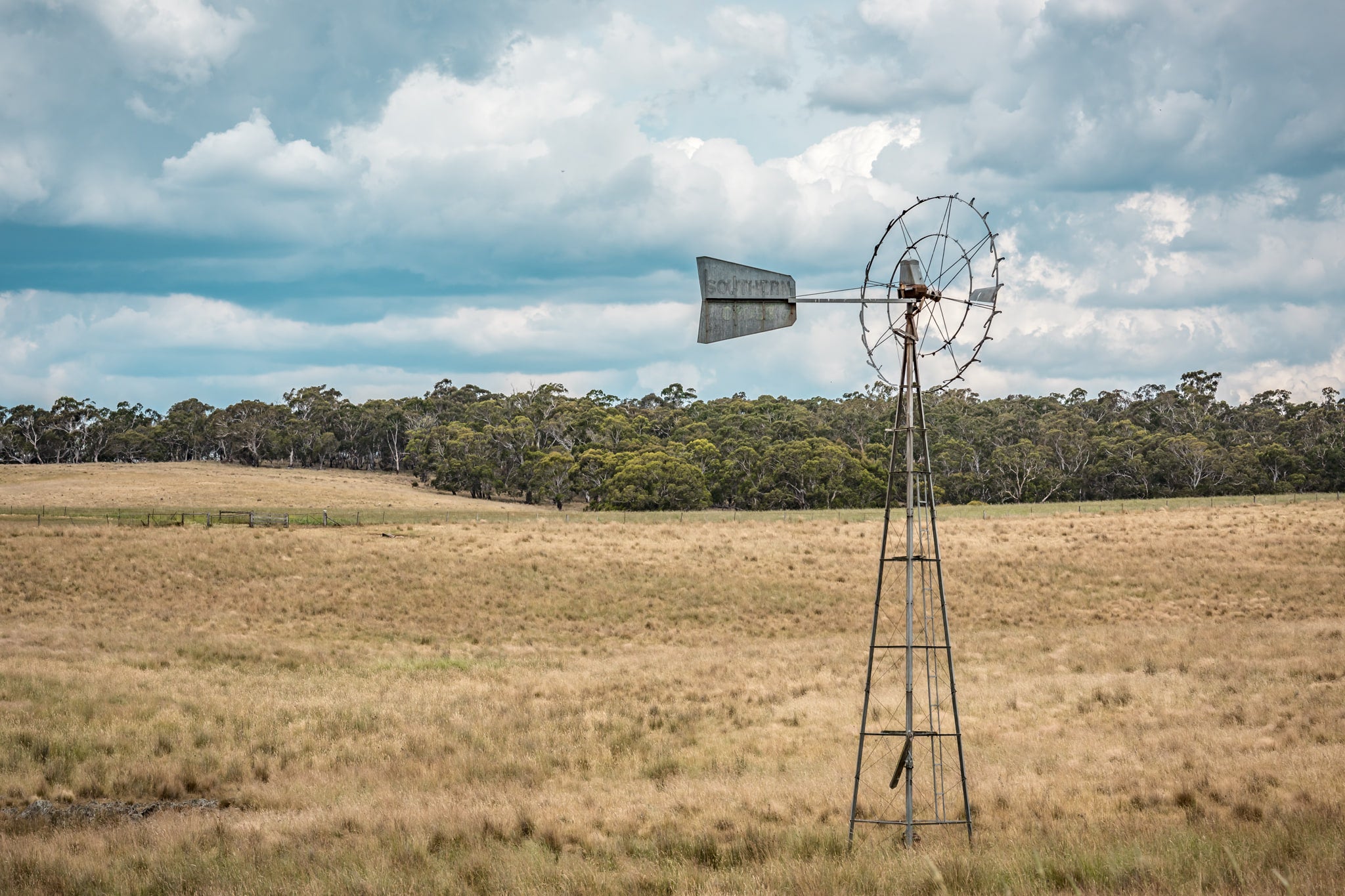 Snowy Mountains Windmill at Landscapes, a lone windmill in a paddock on a cloudy afternoon.