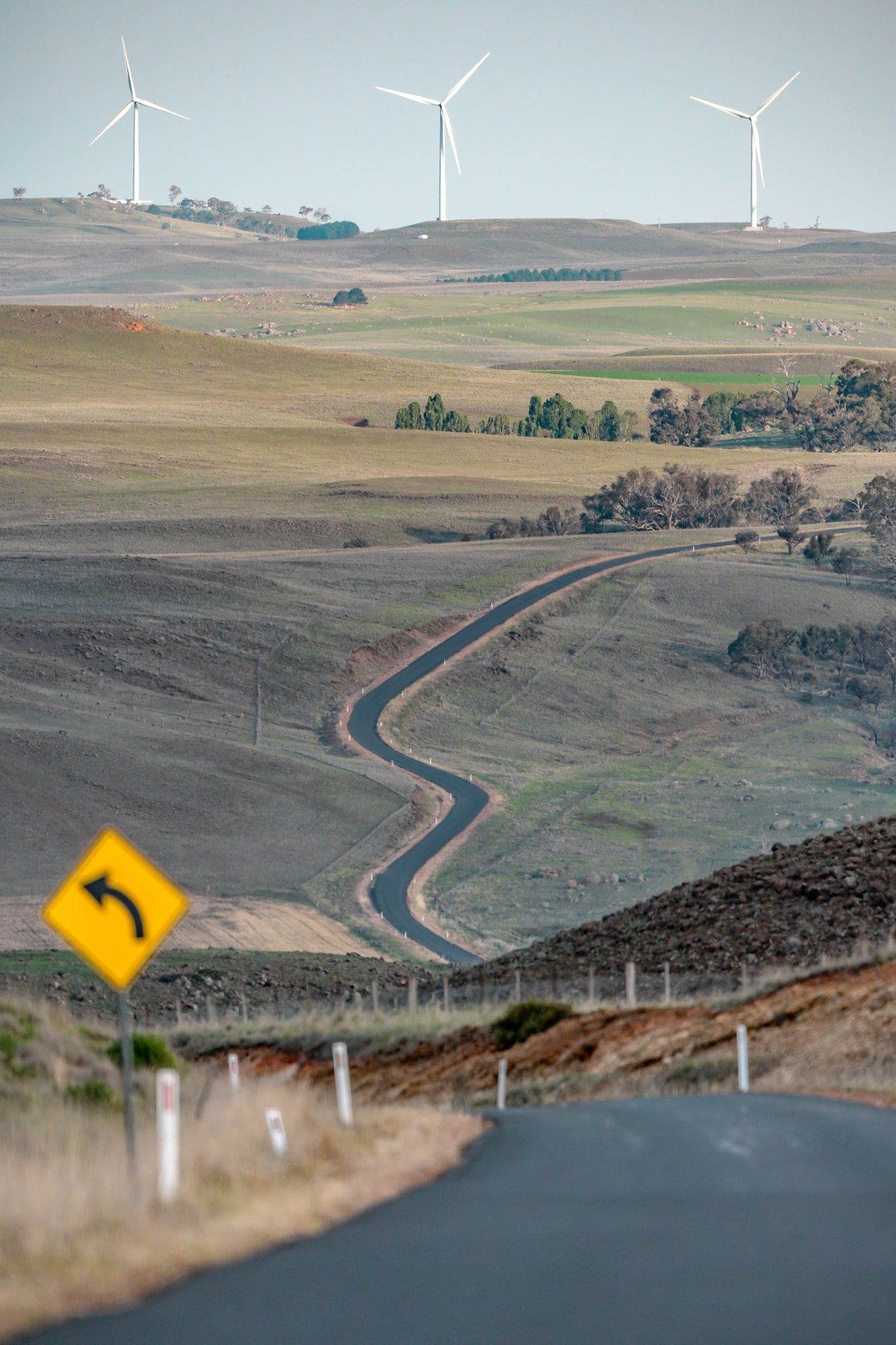 The Snowy River Way at Landscapes, a single lane of asphalt cuts through open grazing country, snaking down into a valley.