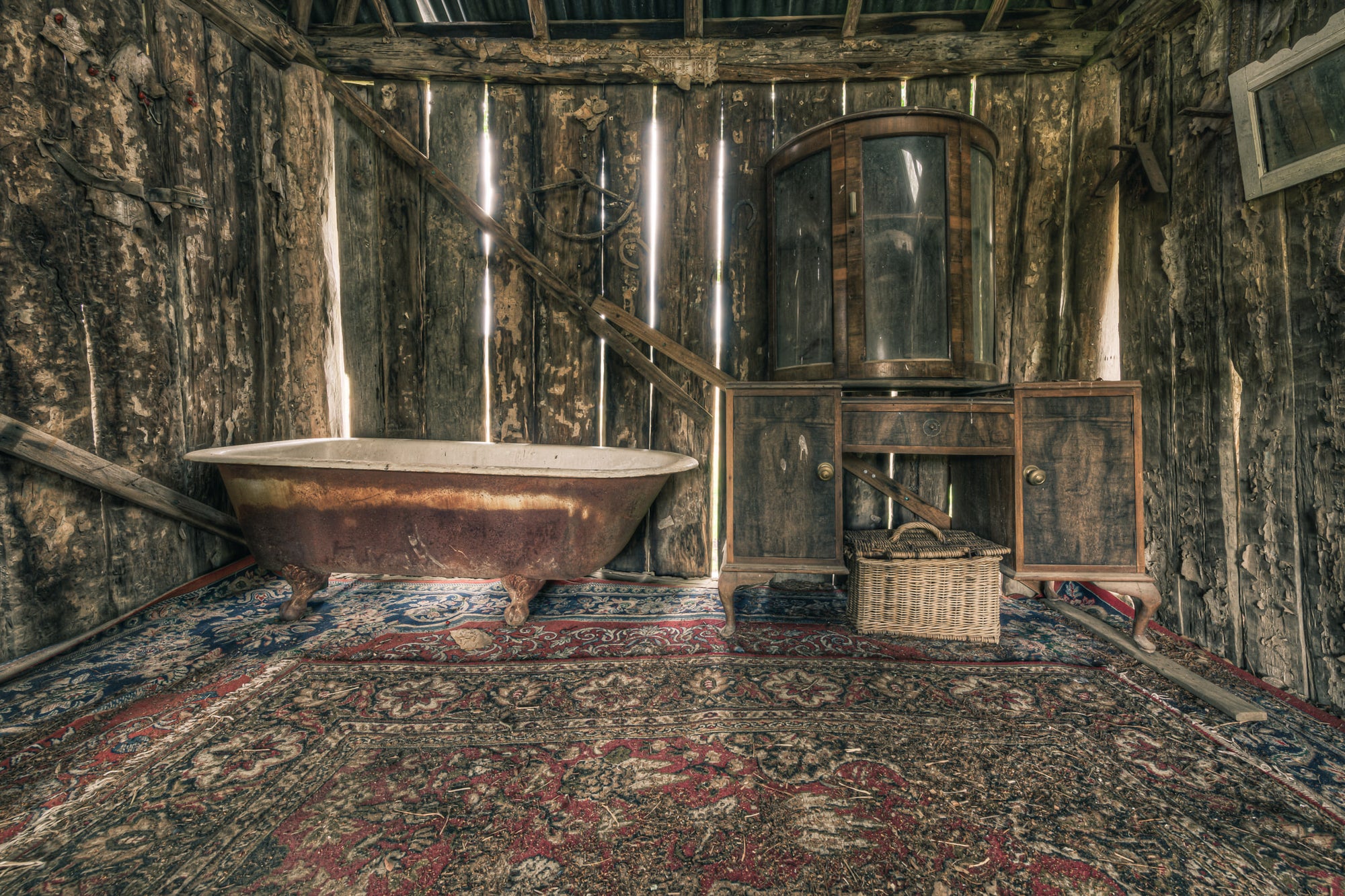 Bath at Leichhardt House, a cast-iron clawfoot bathtub sits on a Persian rug, its enamel interior stained brown with rust.