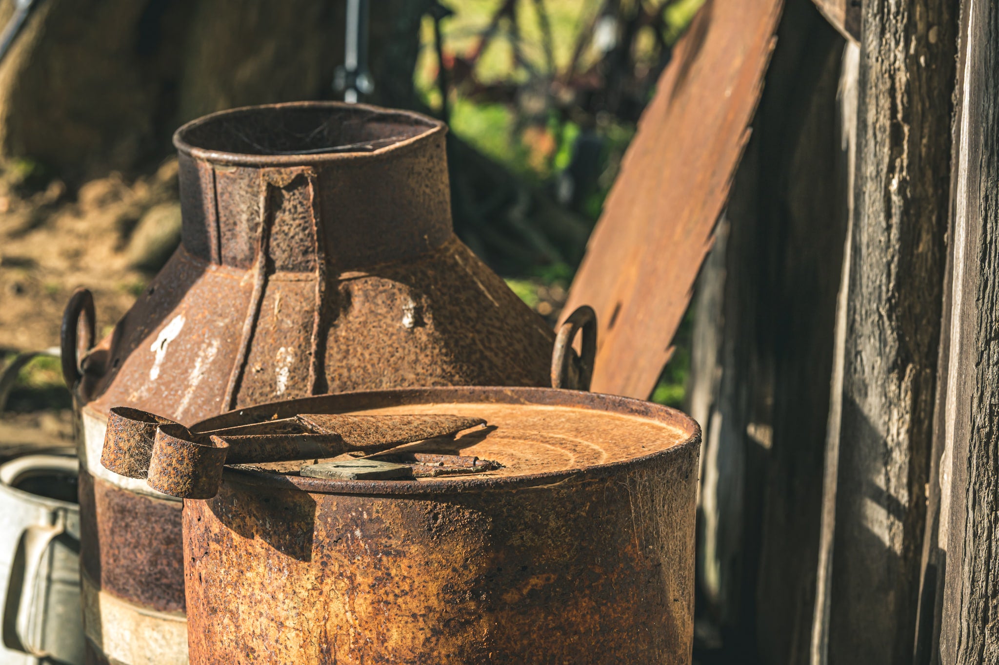 Rust at Leichhardt House, two steel milk cans sit against a weathered timber wall.