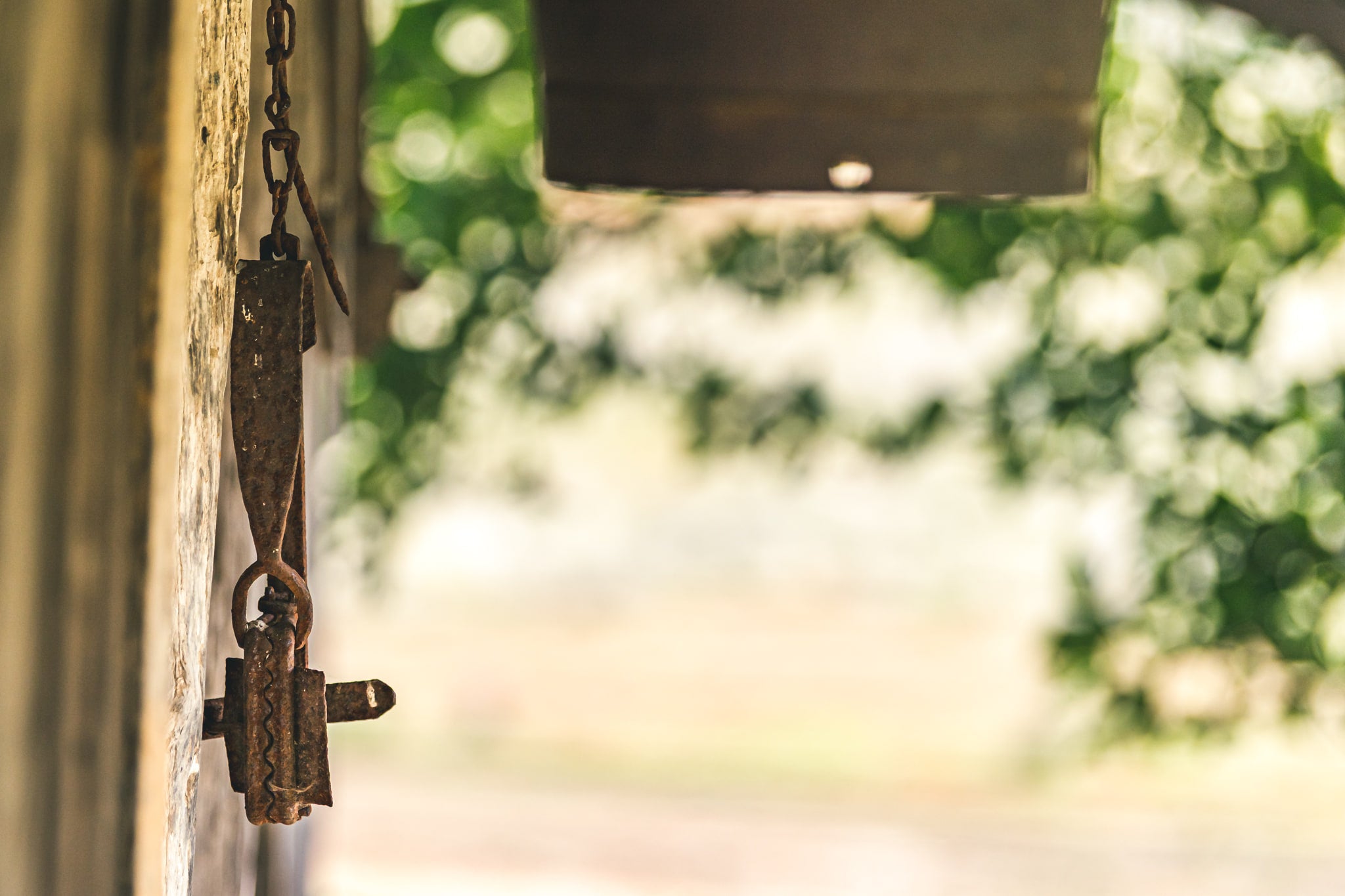 Trap at Leichhardt House, a rusted steel trap hangs from a short chain on a weathered timber post.