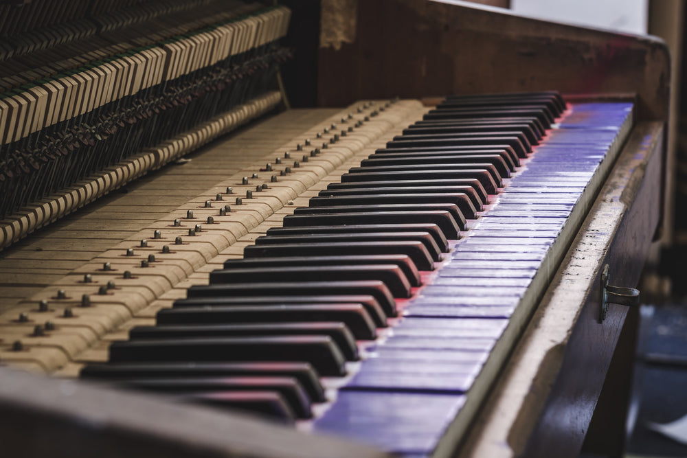 Piano at Macquarie Boys Technology High, an upright piano sits with its front panel removed, exposing the full row of hammers and dampers behind the keyboard.