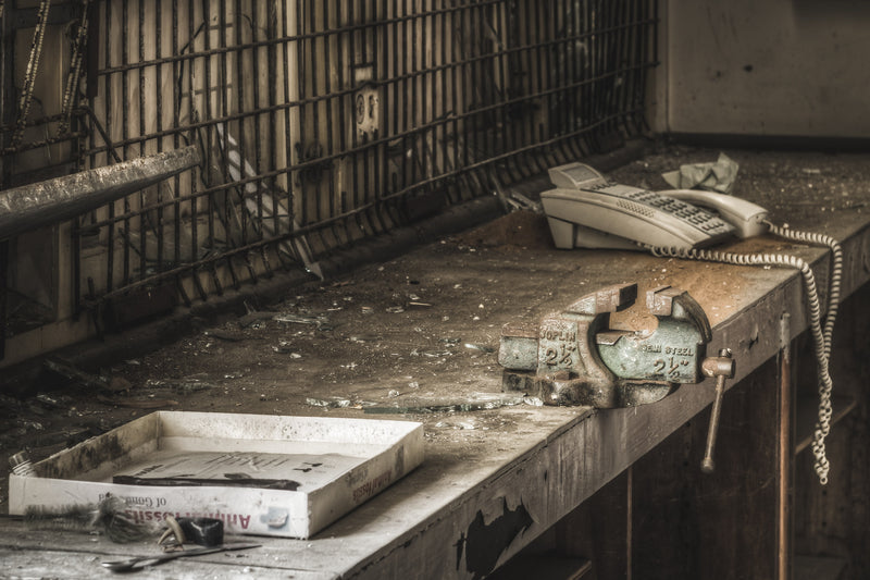 A rusted Joplin 2.5 inch Semi Steel vise sits bolted to a dusty workbench in a chemistry prep area within the maths block at Macquarie Boys Technology High.
