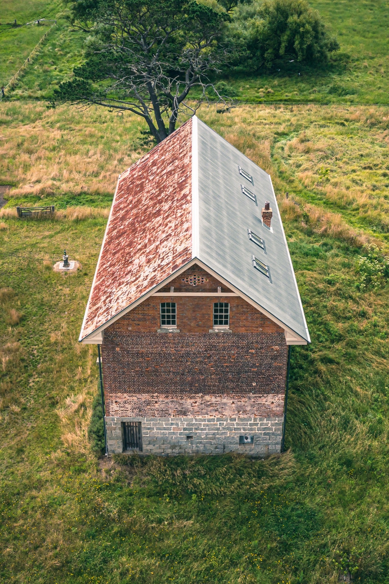Pitched roof and brick gable at Jembaicumbene, copper and grey iron cladding with a brick chimney.