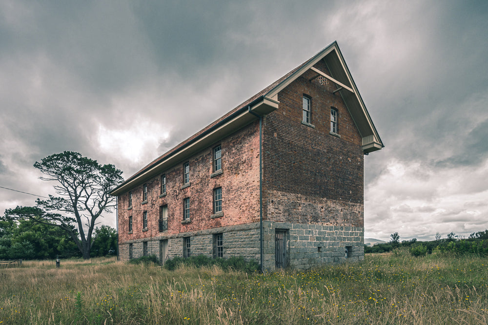 End of the Mill at Mill Pond Farm, a two-storey brick and bluestone building stands alone in open grassland.