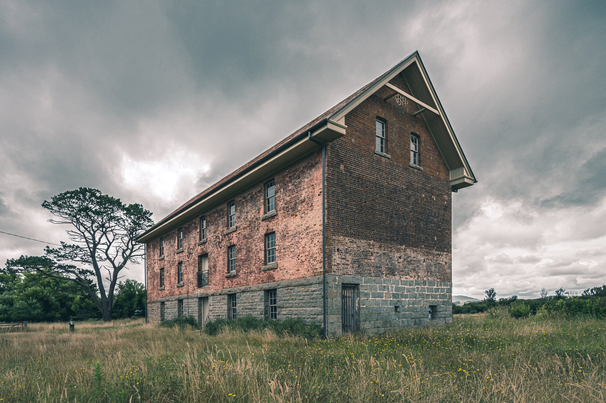 End of the Mill at Mill Pond Farm, a two-storey brick and bluestone building stands alone in open grassland.