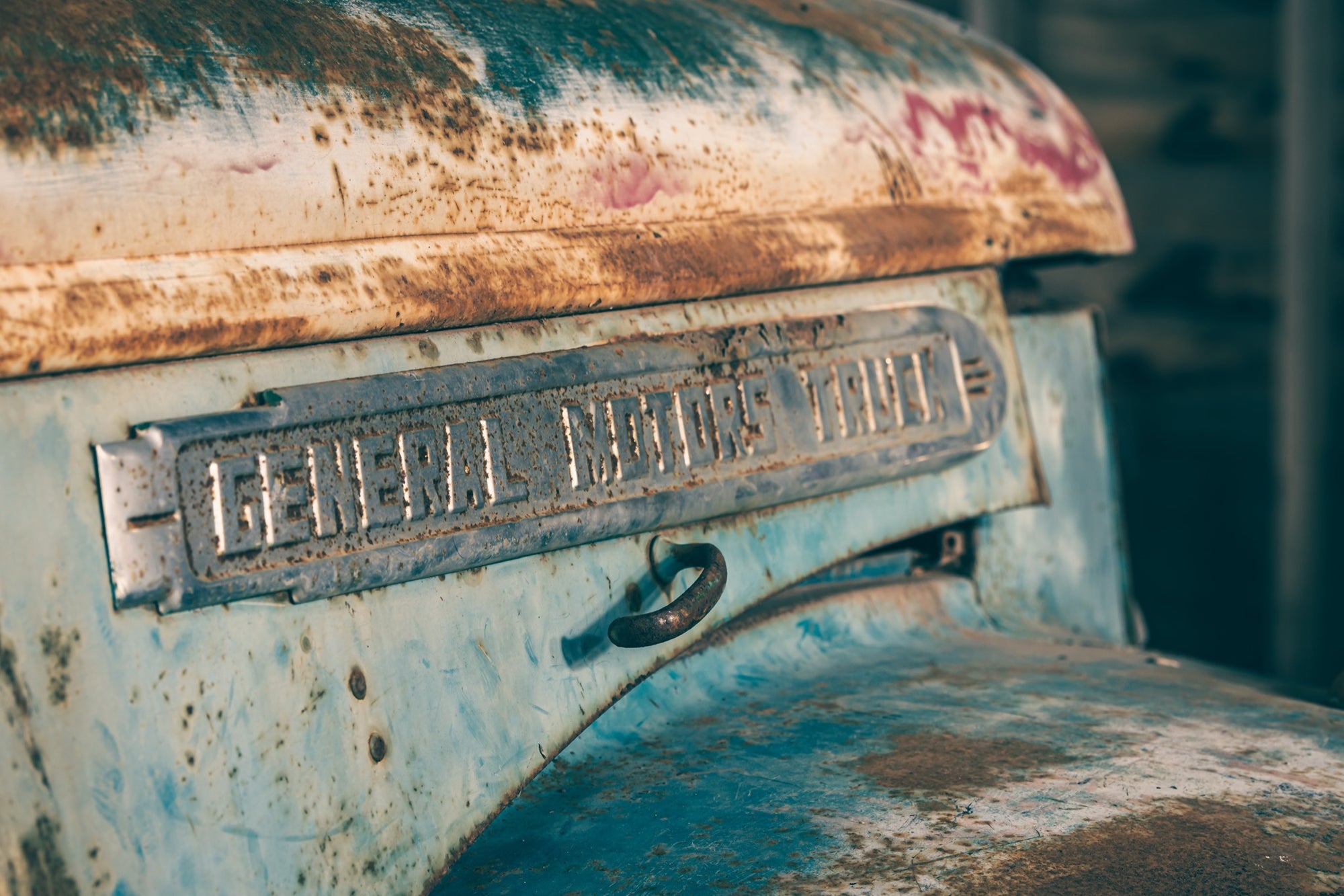 A rust-streaked General Motors Truck nameplate on a corroded faded blue body panel photographed at Jembaicumbene, New South Wales.