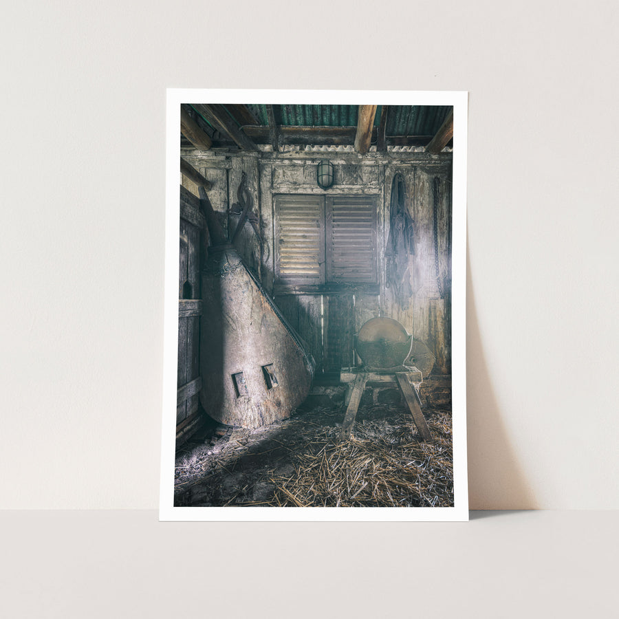 Shed interior at Jembaicumbene, a stone grindstone on a timber frame beside a conical metal vessel.