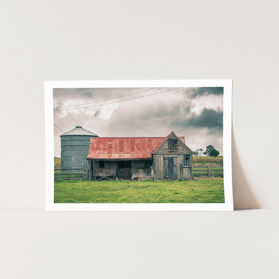 Timber stable at Braidwood, rusting red iron roof beside a tall grey grain silo.