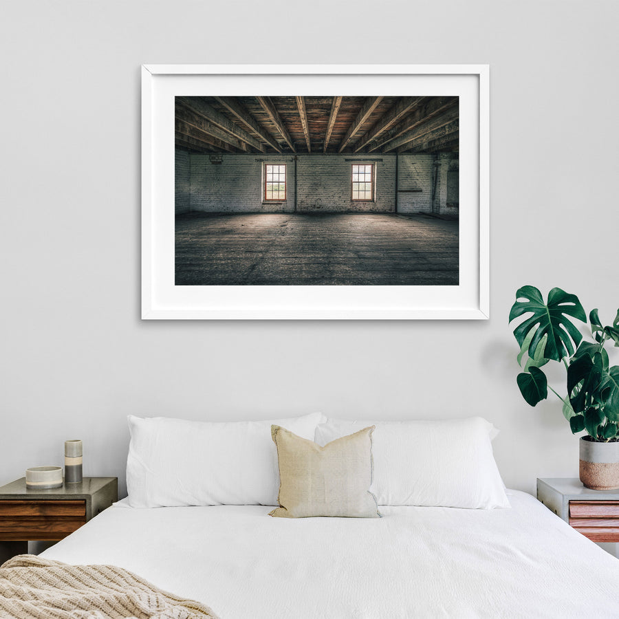 Upper room at Jembaicumbene grain store, two sash windows in a whitewashed brick wall under timber beams.